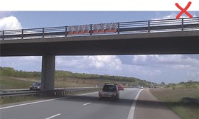 Ulovlig ophængning – ulovligt opsatte plakater på ydersiden af bro over skærende vej
